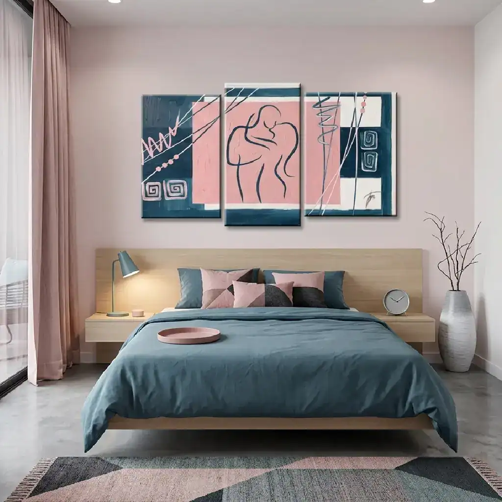 Quadro trittico moderno "Bacio Avvolgente" appeso alla parete di una camera da letto contemporanea, coordinato con lenzuola blu e pareti rosa.